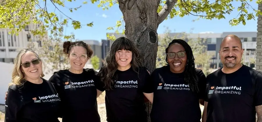 The Impactful Organizing team in matching black T-shirts, smiling outdoors